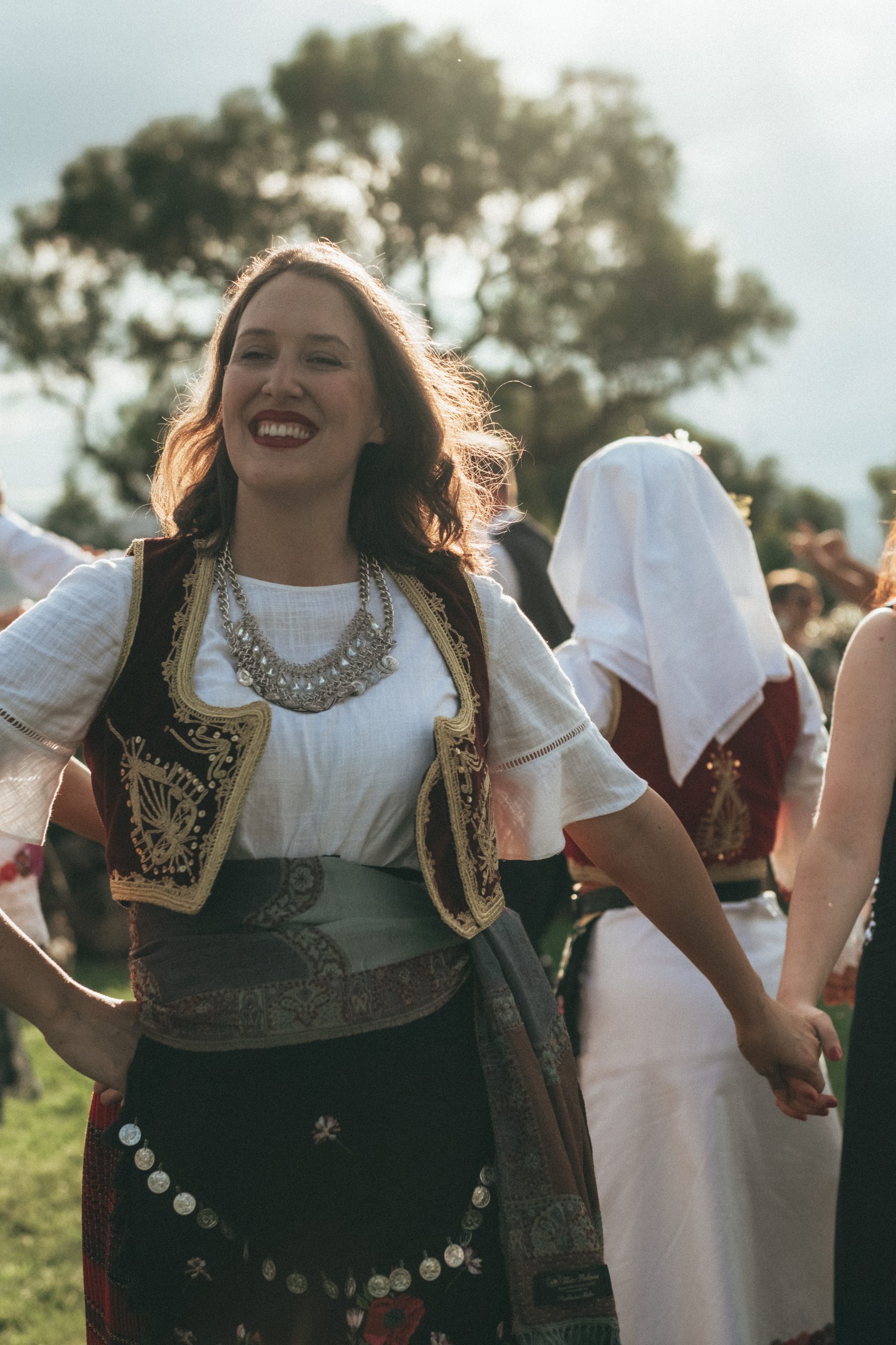 A woman dressed in Serbian traditional dress, smiling,